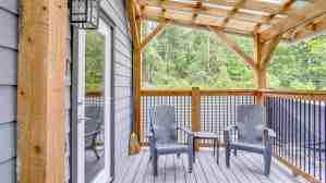 Covered cabin patio with Adirondack chairs overlooking the forest at Chims Cabins in Port Alberni